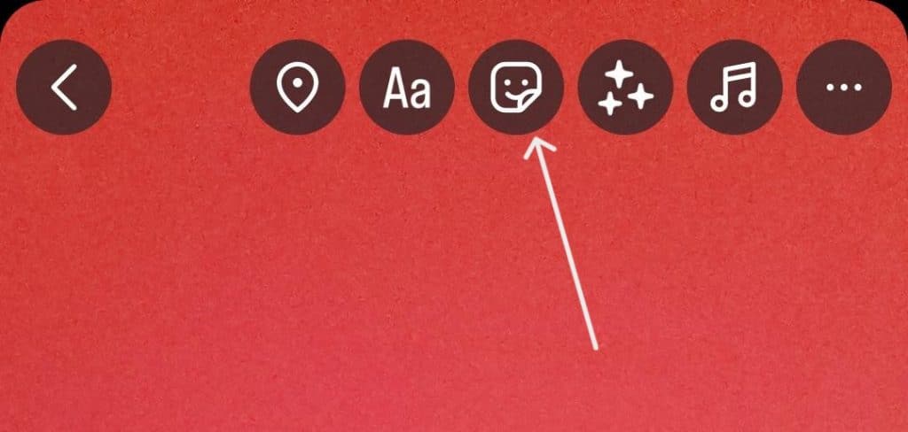 Screenshot of Instagram story editor with a white arrow pointing to the smiley sticker icon at the top menu.
